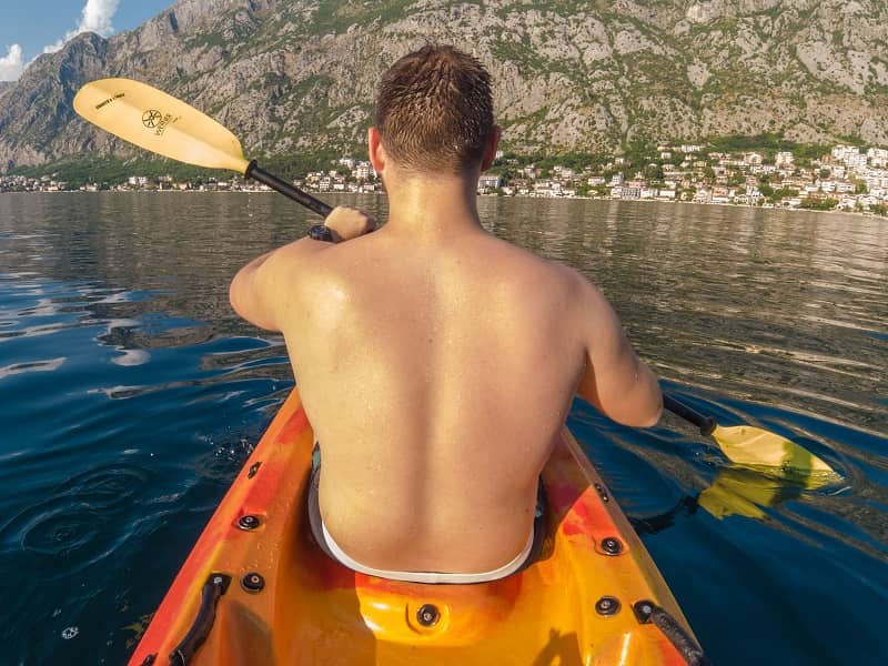 Young guy during the kayak tour in Kotor bay, with mountain in front of him